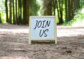 Join us symbol. Concept word Join us on white chalk background. Beautiful forest background....