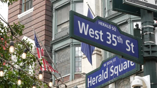 New York City crossroad, Manhattan Broadway street intersection road sign. NYC Midtown district architecture, Herald Square park, 6 Sixth avenue, United States. American flag. One way arrow road sign.