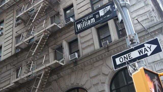 New York City crossroad, William street intersection road sign. NYC Manhattan downtown financial business district architecture, United States. Corner roadsign, house with fire ladder, traffic light.