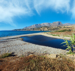 Small river flows into the sea on pebble beach