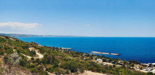 Panoramic view of a beautiful coastline of Black sea in Bulgaria with a winding road, lush greenery, and the deep blue sea under a clear sky. Ideal for travel, nature, and landscape themes.