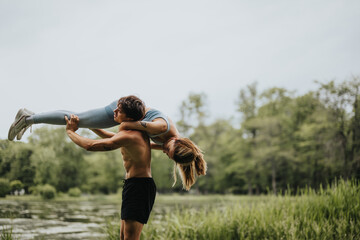 Man lifting his female partner in a park, demonstrating fitness, strength, and outdoor exercise