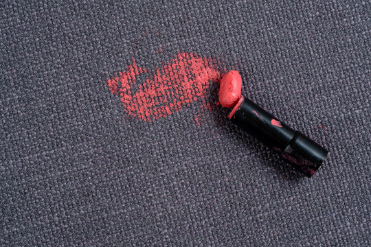 Broken lipstick. Dirty pink lipstick stains on a white background carpet and on upholstery. Cleaning of makeup stains. life stain concept. top view