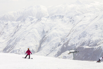 A male snowboarder rides on a snowboard slope on a sunny winter day at the Gudauri ski resort in Georgia