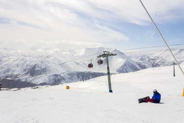A male snowboarder rides on a snowboard slope on a sunny winter day at the Gudauri ski resort in Georgia