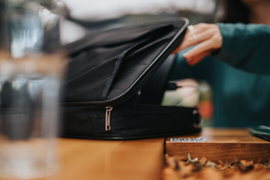 Close-up of a female professional organizing documents in a briefcase on a wooden table - Powered by Adobe