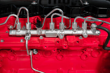 A red engine with a silver hose coming out of it. The hose is attached to a black pipe