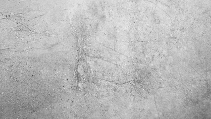 A grey wall with a lot of cracks and holes. The wall is made of concrete and has a rough texture