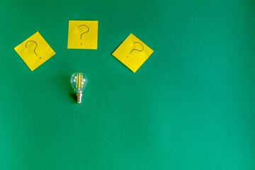 light bulb and question marks on a beautiful dark green background, idea concept