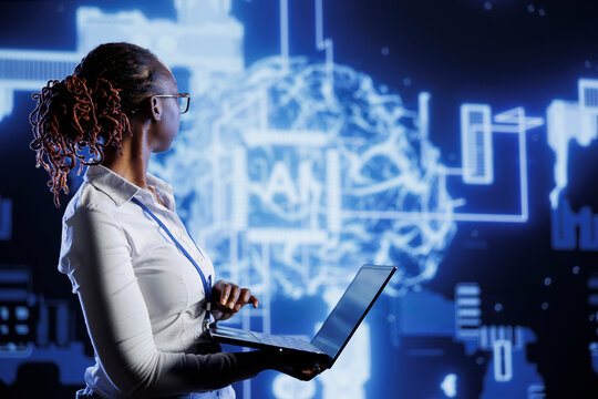 IT consultant uses laptop to develop artificial intelligence neural networks nodes modeled after human brain. Server room worker setting up AI machine learning accurately making predictions using data