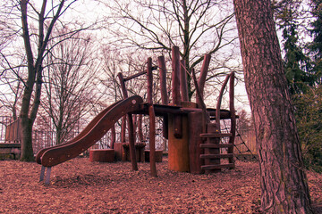 Empty playground. Wooden playground with a slide in the park. Children's playground in cold...