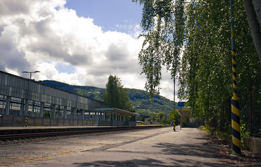 Abandoned train station. Train station without people. Platform, tracks, underpass. In the background Nature with blue sky and clouds. Mountains, forests, white clouds.