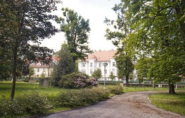 A park with a concrete sidewalk and leading to a residential area. The end of the park with a view of the old brick houses. Historic urban development with a park.