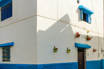 Close up of blue and white walls of the Rabat Medina house with flower pots hanging