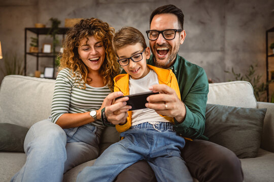 mum, dad and son play video games together on mobile phone at home