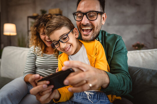 mum, dad and son play video games together on mobile phone at home