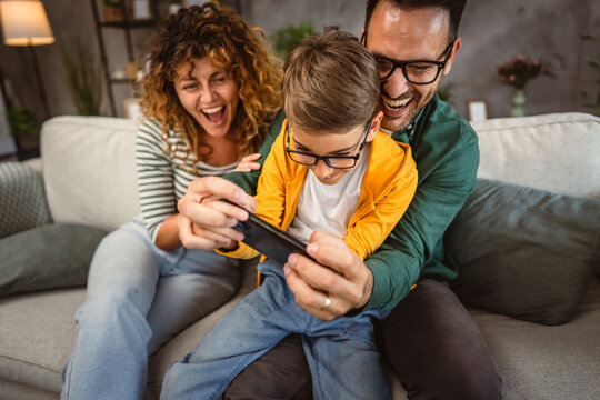 mum, dad and son play video games together on mobile phone at home