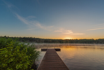 Fototapeta premium Small forest lake covered with fog at sunrise on June morning