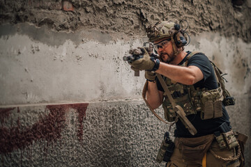 Fototapeta premium Portrait of soldier shot with sniper rifle at abandoned building.
