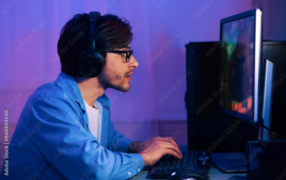 Poster a man is sitting in front of a computer with headphones on, playing a video game. he is focused on t