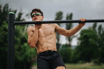 Fit man performing pull ups at an outdoor gym, showcasing biceps, shoulder, and lateral muscle training.