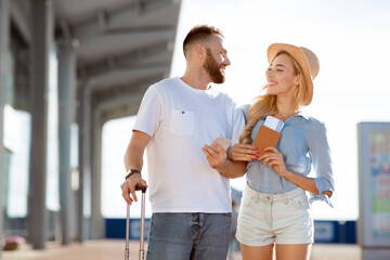Newlyweds arriving at airport, going on honeymoon and holding tickets outdoors, free space