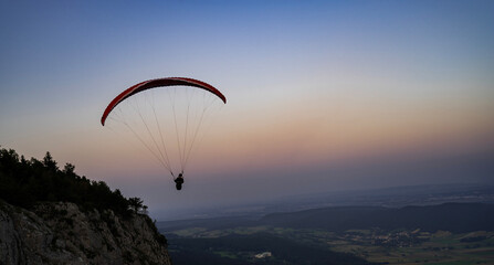Paragliding concept, a paraglider pilot fly in the sky at sunset on the nature mountain landscape background.