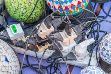 Old and damaged electric adapter power plug has many appliances are plugged outlet socket concept of risk danger overloaded current electrical. Overloaded power plugs, close up