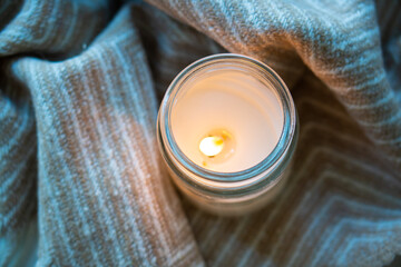 The image shows a top view of a lit candle with a blanket, creating a cozy and warm atmosphere