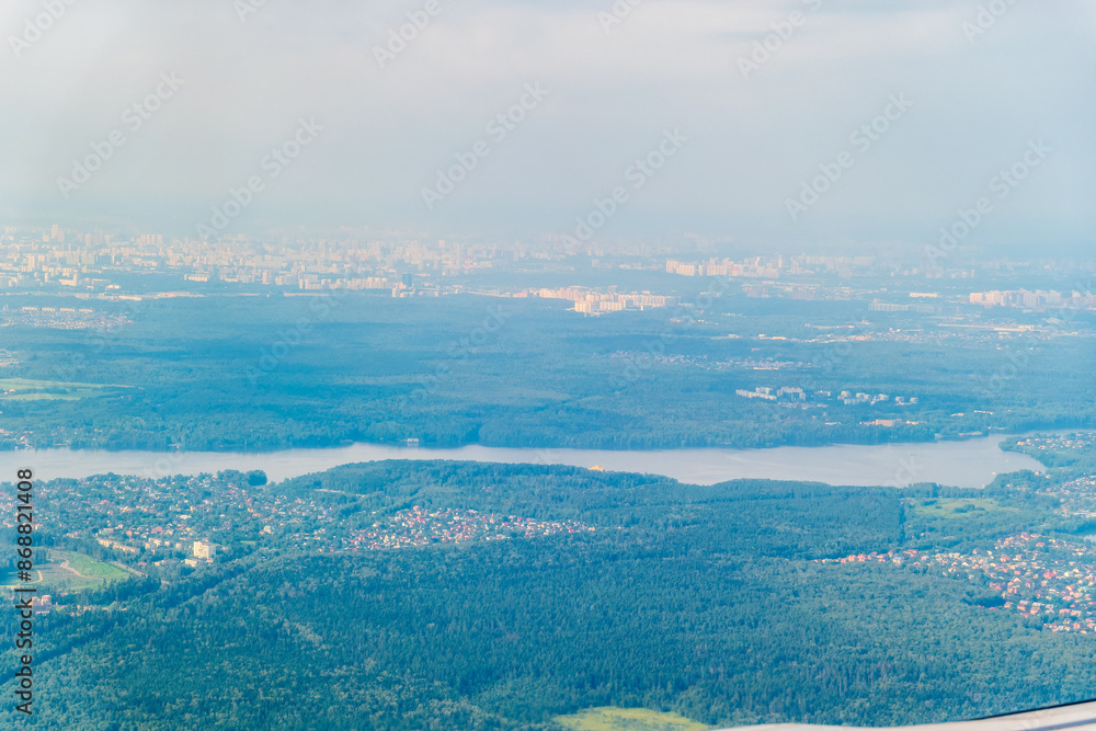 Wall mural view of airplane wing, blue skies and green land during landing. airplane window view.