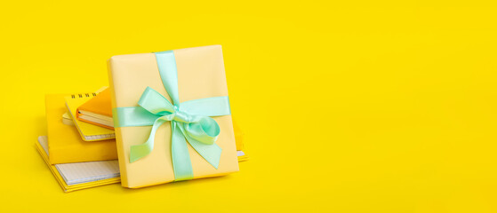 Gift box with different notebooks on yellow background