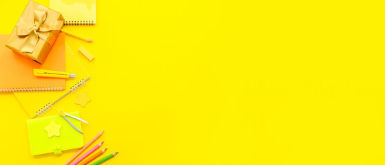 Gift box with different stationery on yellow background