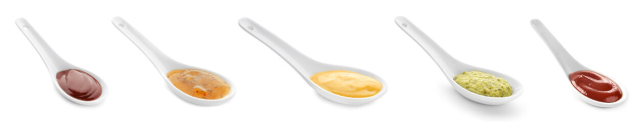 Set of spoons with tasty sauces on white background