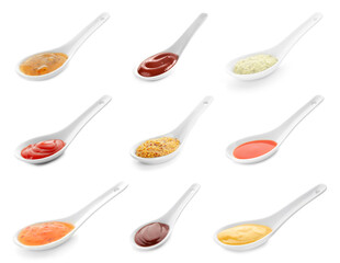 Group of spoons with tasty sauces on white background