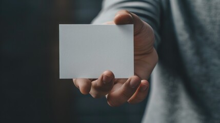 Obraz premium A person holds a blank business card, suitable for use in presentations, resumes, and more