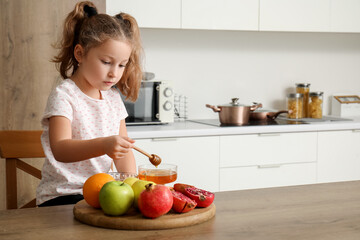 Cute little girl with ripe fruits and honey in kitchen. Rosh Hashanah (Jewish New Year) celebration