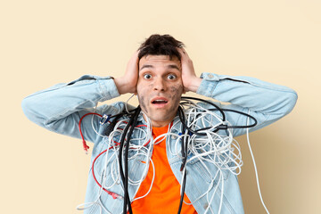 Electrocuted young man with burnt face and wires on beige background