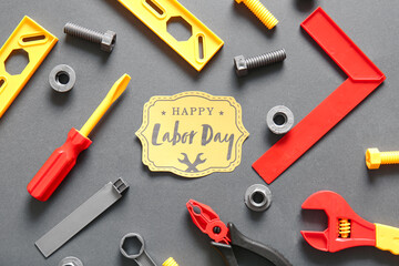Greeting card with text HAPPY LABOR DAY and toy tools on grey background. Labor Day celebration
