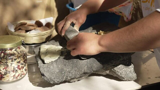 Close up woman making nixtamal for tortillas the mexican traditional way with a molcajete