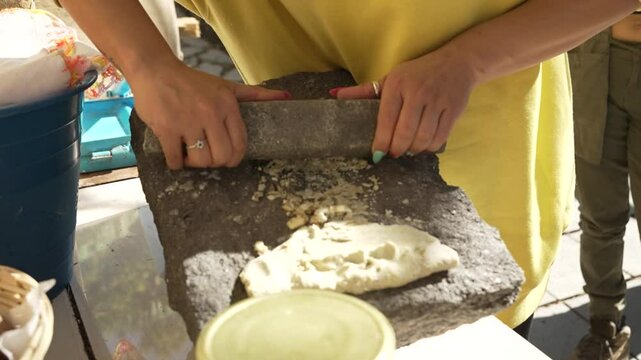 Close up young fancy girl trying to make nixtamal for tortillas, the traditional mexican way with a molcajete