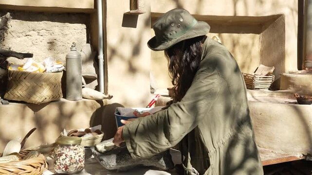 Mexican young gril trying to make nixtamal the traditional mexican way with a molcajete