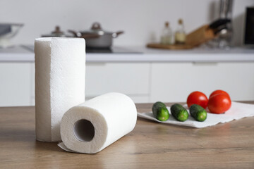 Rolls of paper towels and vegetables on table in kitchen, closeup