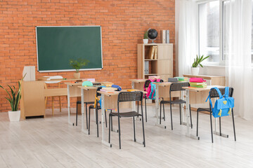 Interior of classroom with chalkboard, desks and backpacks