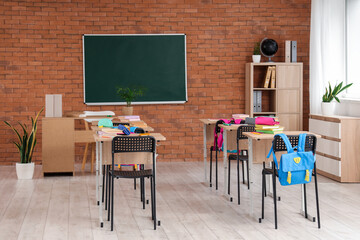 Interior of classroom with chalkboard, desks and backpacks