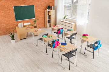 Interior of classroom with chalkboard, desks and backpacks