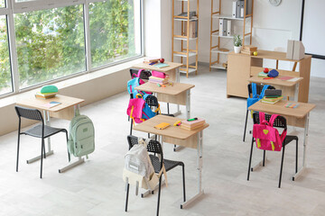 Interior of light classroom with desks and backpacks