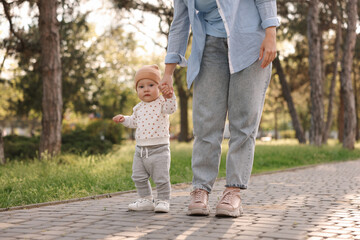 Obraz premium Mother supporting her baby while he learning to walk outdoors, closeup