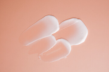 Creamy lotion smears on a smooth, peach-colored backdrop for skincare and cosmetic beauty products concept.