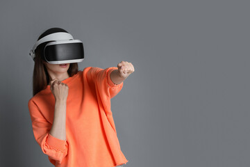 Woman using virtual reality headset on gray background, space for text