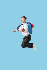 Little schoolboy with apple jumping on blue background
